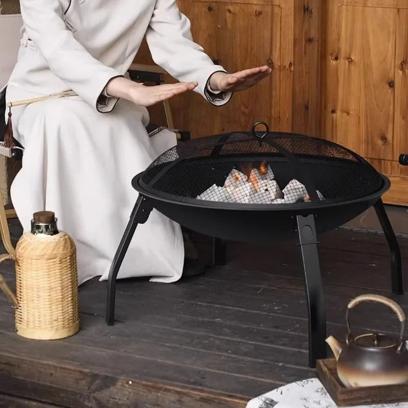 Portable outdoor camping wood stove with removable circular grill for campfire cooking and firewood burning.